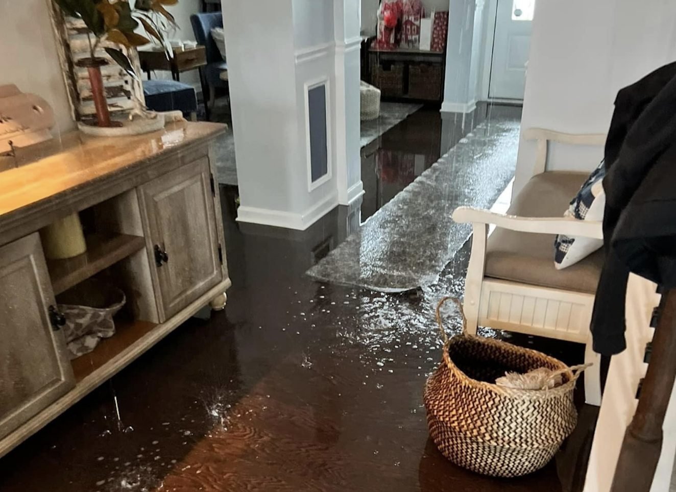 Active water flooding across hardwood floors in a Charlotte NC home after a burst pipe