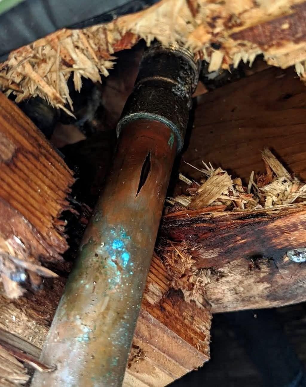 Close-up of a burst copper pipe found in an attic during a Charlotte NC water damage call